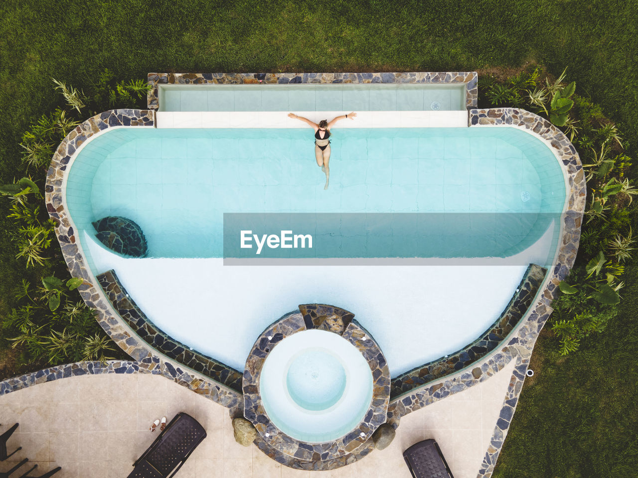 Top view woman alone in a swimming pool enjoying a sunny summer day