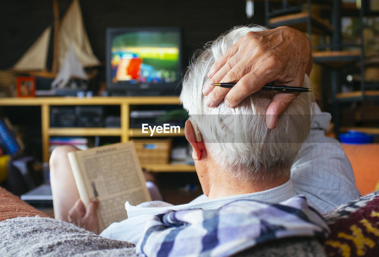 Close-up of man with book sitting at home