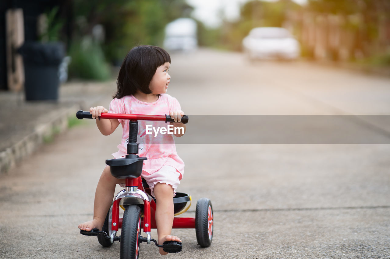 FULL LENGTH OF A WOMAN RIDING MOTORCYCLE ON FOOTPATH