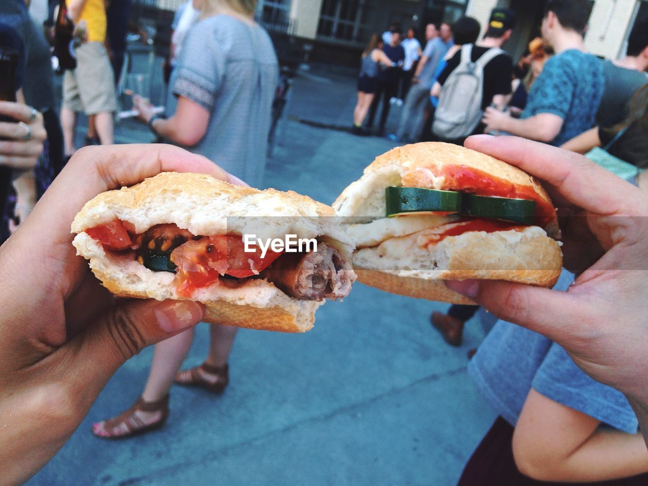 Cropped image of hands holding sandwich on street