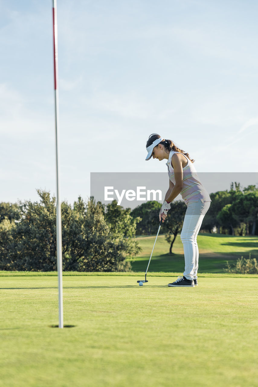 Full length of woman playing at golf course