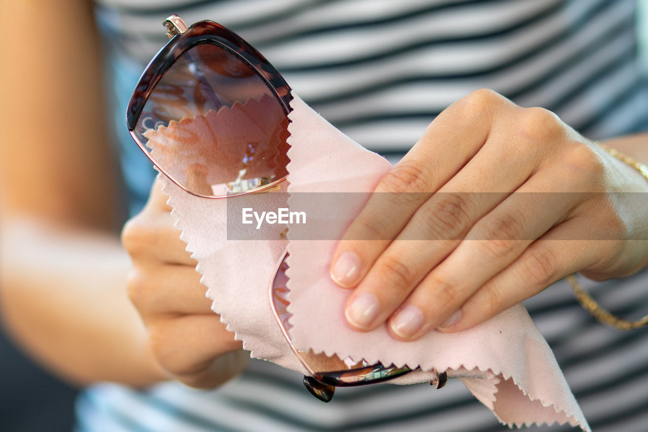 Midsection of woman cleaning sunglasses 