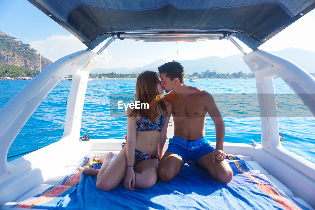 Young couple kissing on boat in sea
