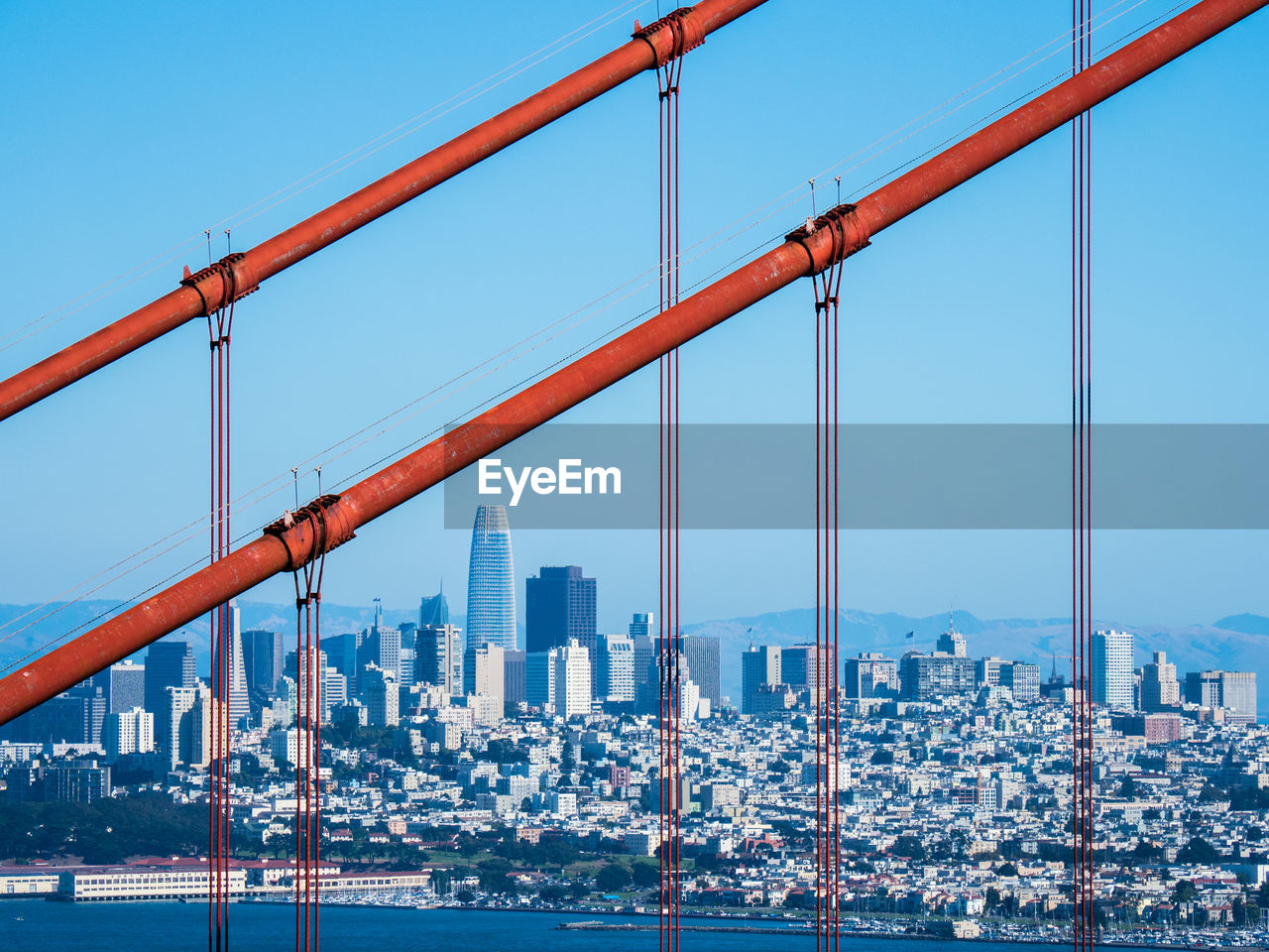 Skyline of downtown san francisco, seen through the red cables of the golden gate bridge