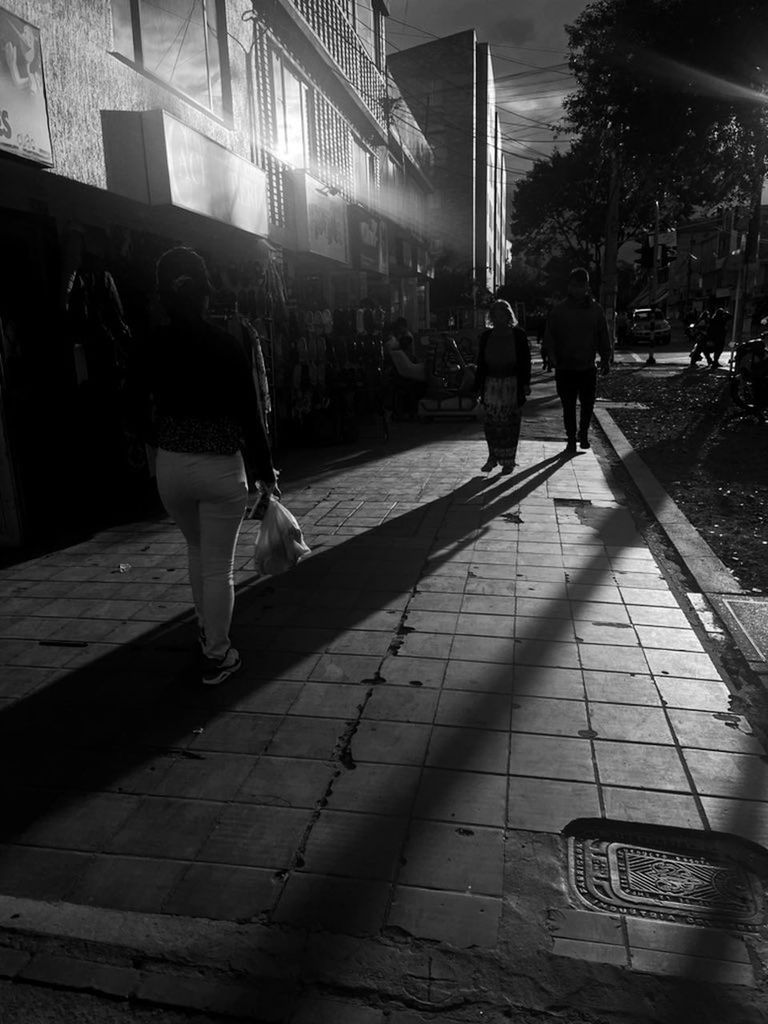 black, darkness, white, light, architecture, black and white, city, night, built structure, monochrome, street, building exterior, monochrome photography, road, shadow, walking, full length, footpath, adult, lifestyles, snapshot, men, women, nature, city life, group of people, infrastructure, sidewalk, leisure activity, outdoors, rear view, transportation