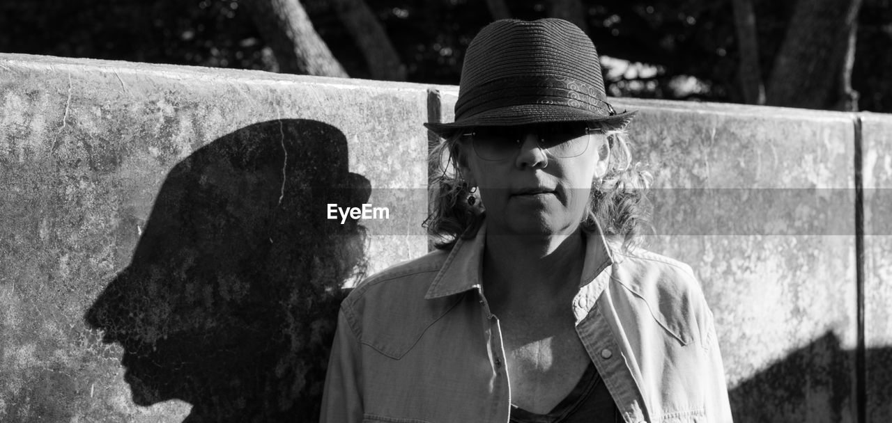 Portrait of mature woman wearing hat against wall