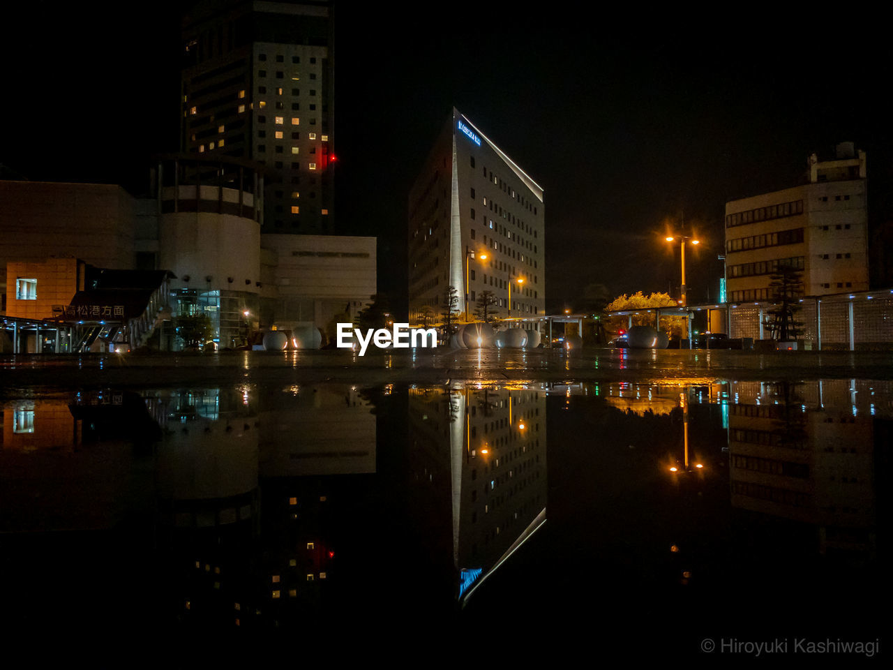 ILLUMINATED BUILDINGS BY RIVER AT NIGHT