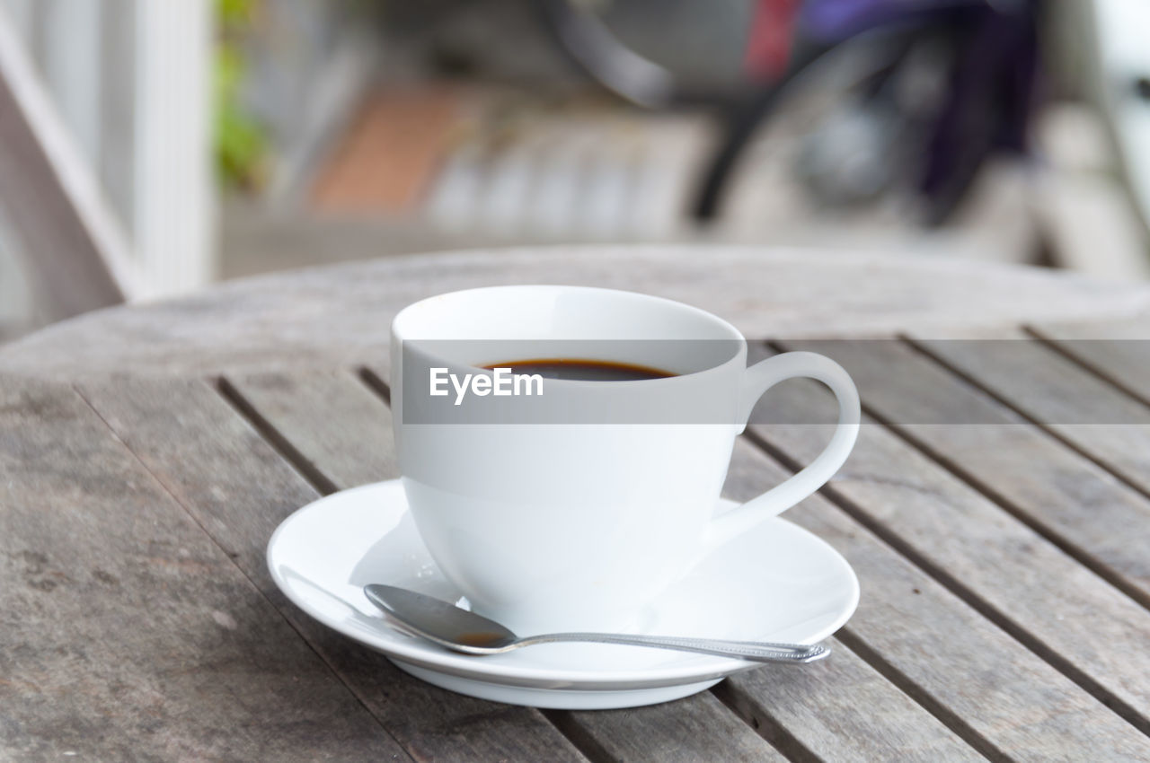 High angle view of fresh coffee served in white cup and saucer on wooden table