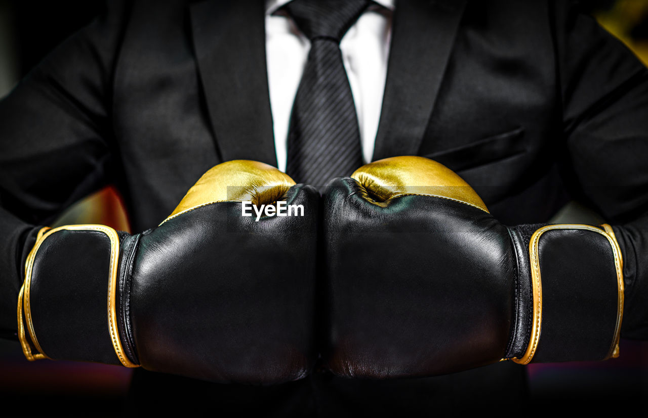 Close-up of midsection of businessman wearing boxing glove