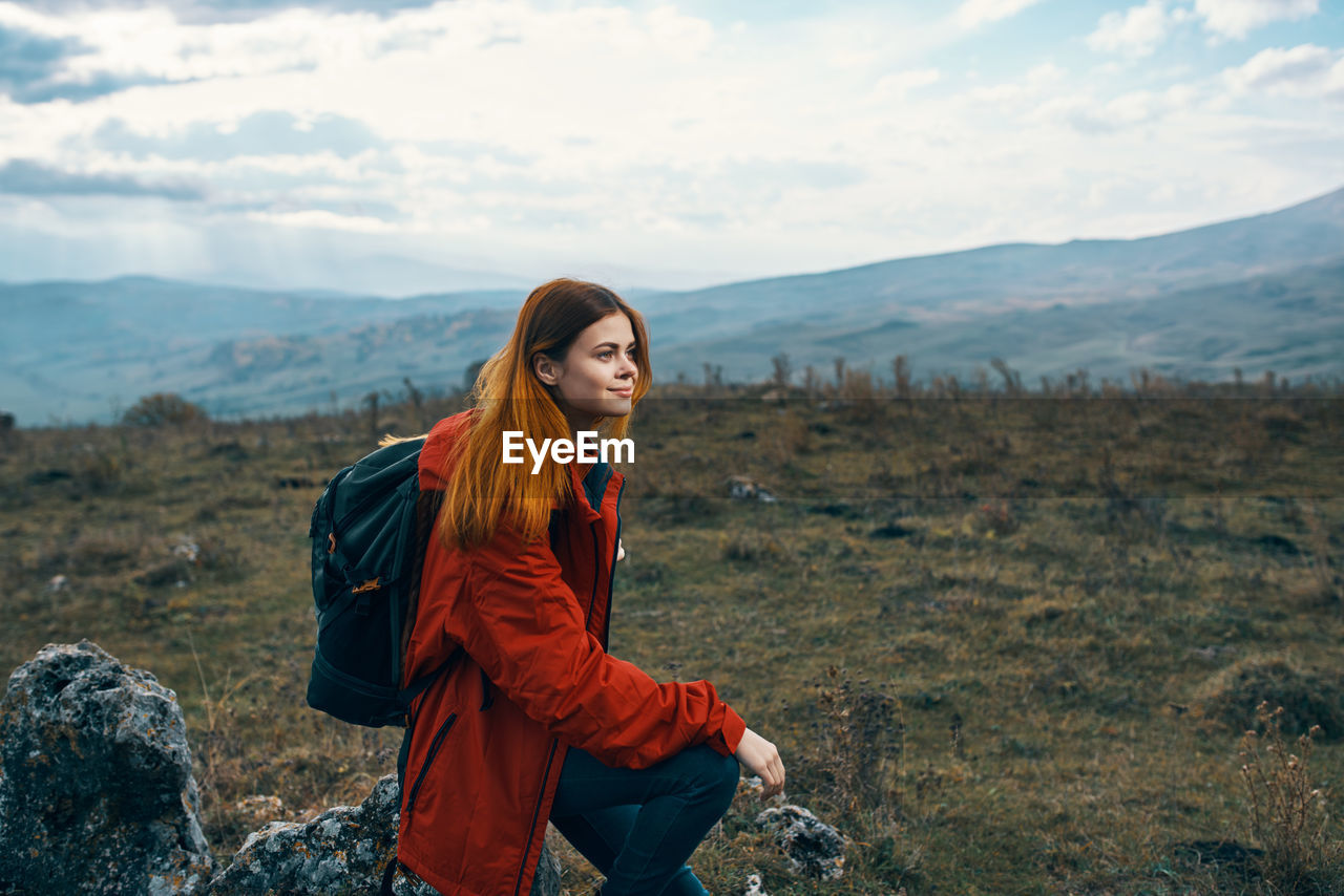 Young woman standing on mountain against sky