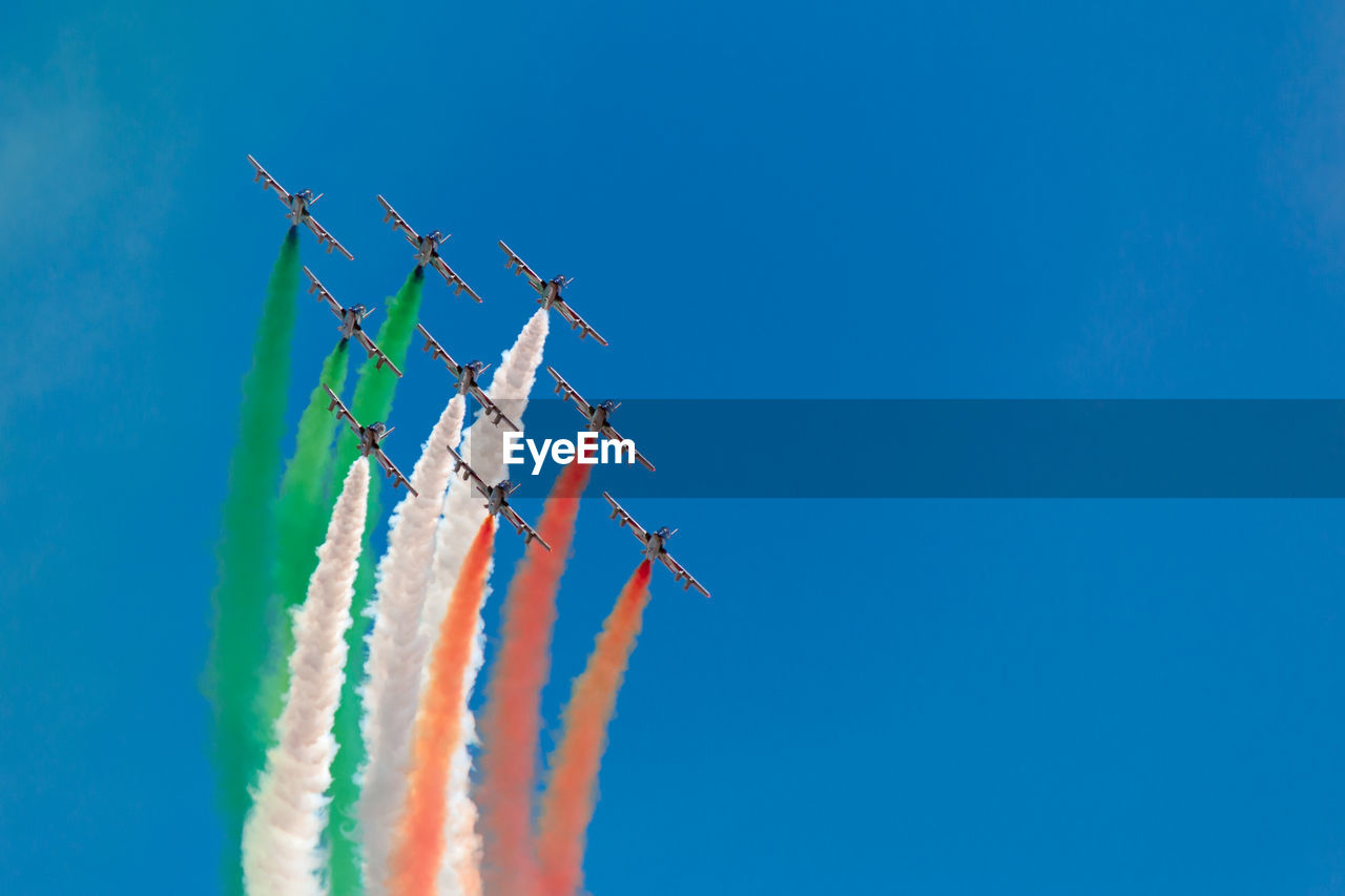 Low angle view of airshow against clear blue sky