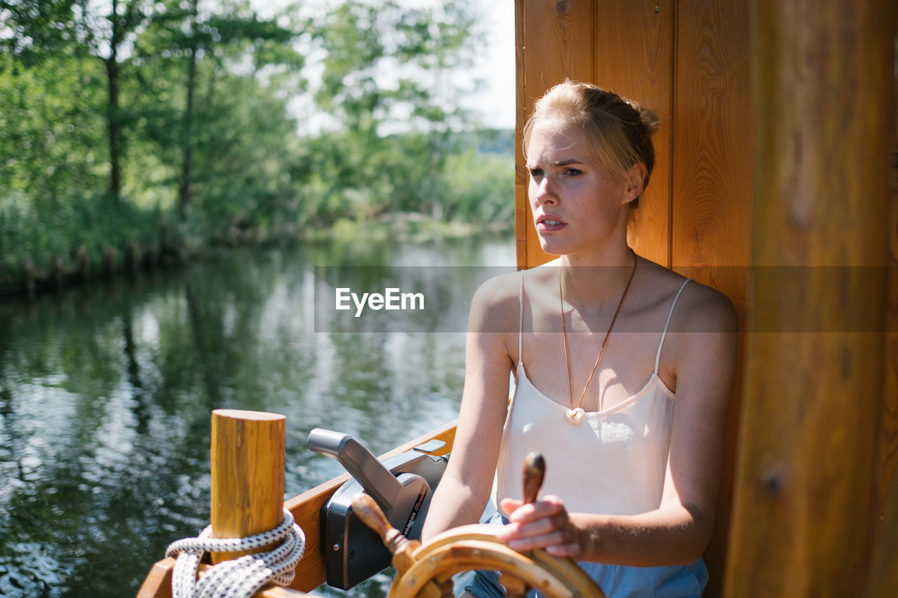 Woman sitting by wheel in boat on lake