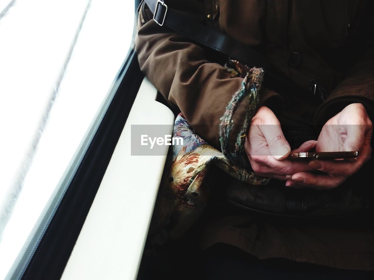 Cropped image of woman using phone while sitting in train
