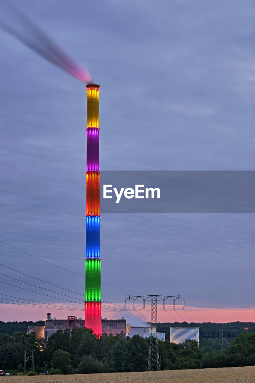 LOW ANGLE VIEW OF ILLUMINATED TOWER AGAINST SKY AT DUSK