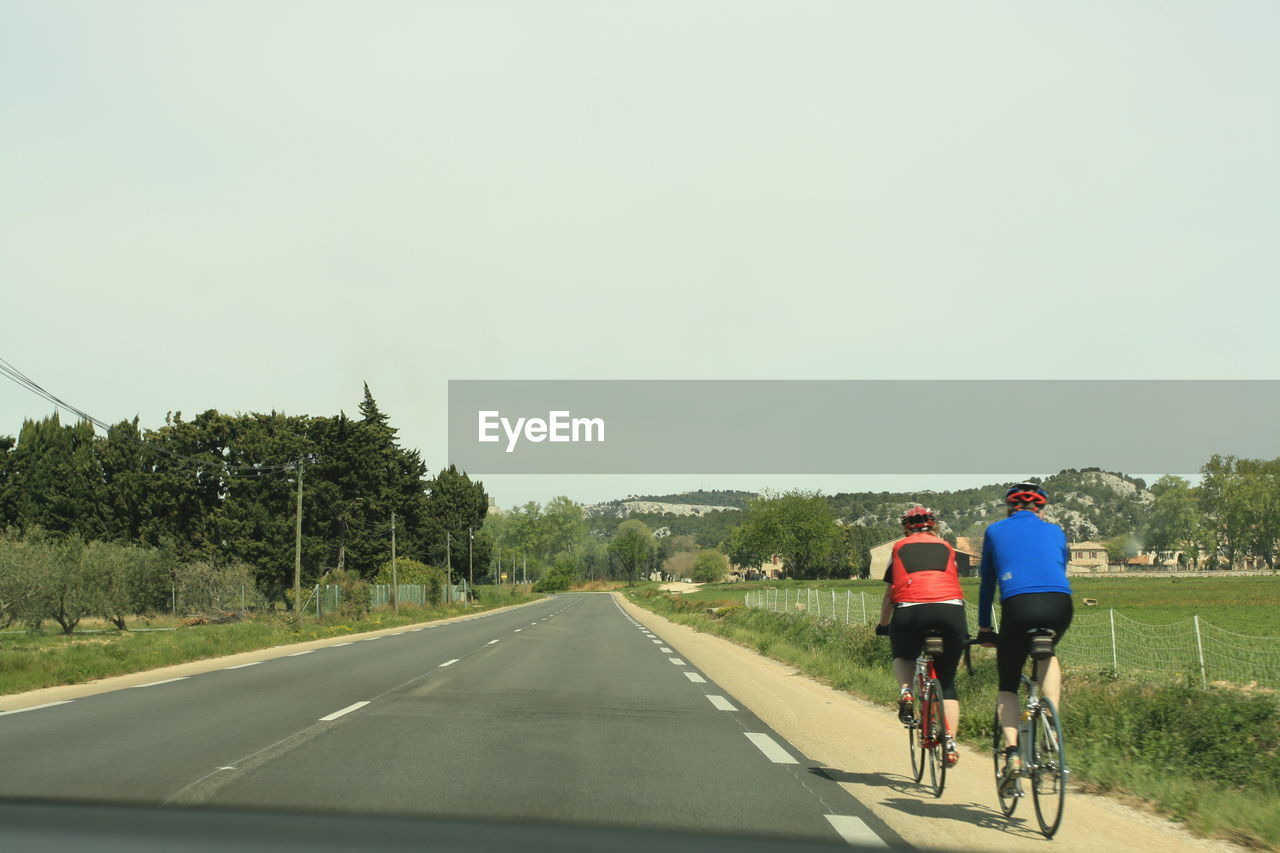 REAR VIEW OF MAN RIDING BICYCLE