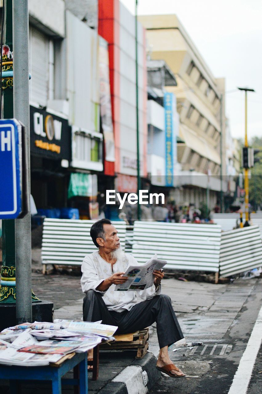 Man selling newspapers in city