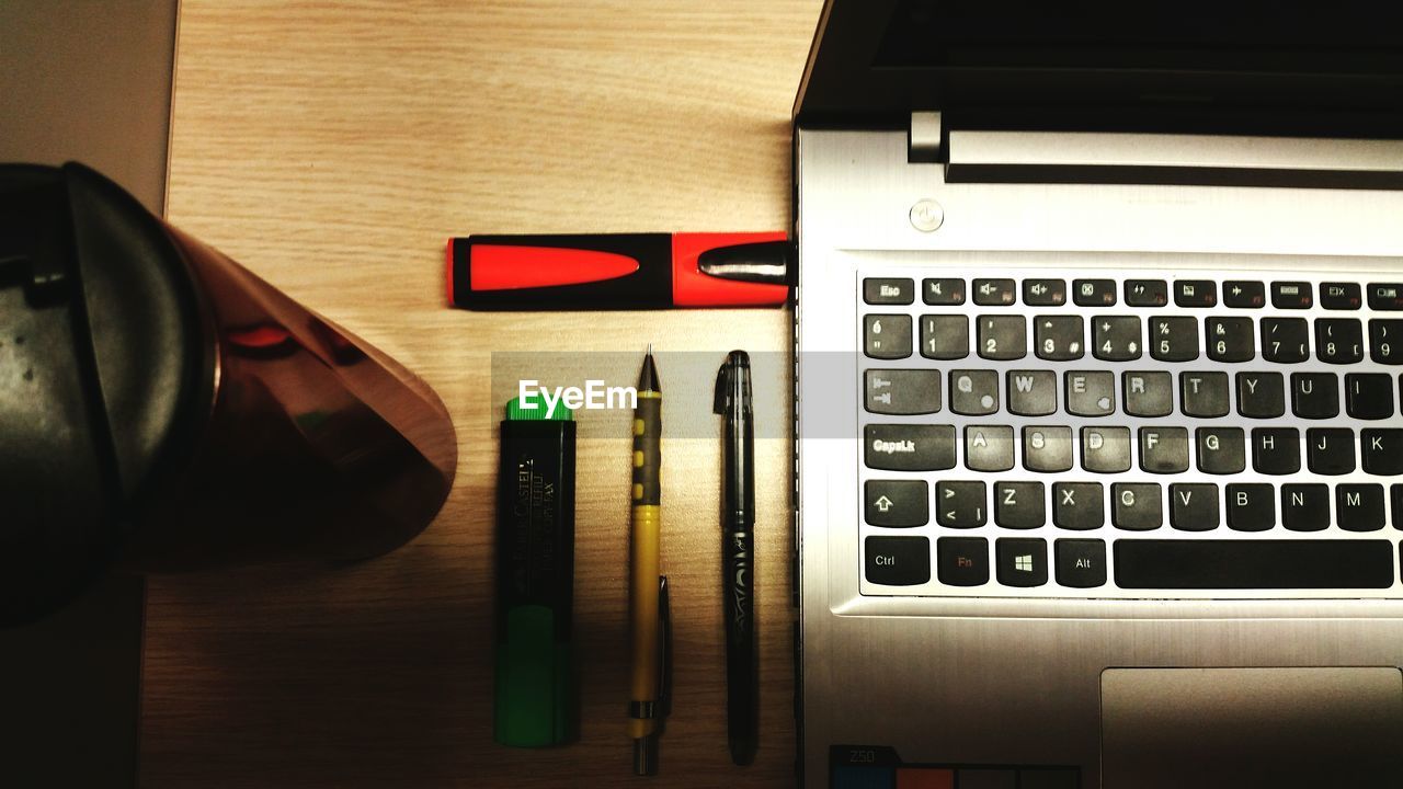 High angle view of pens and bottle by laptop on table