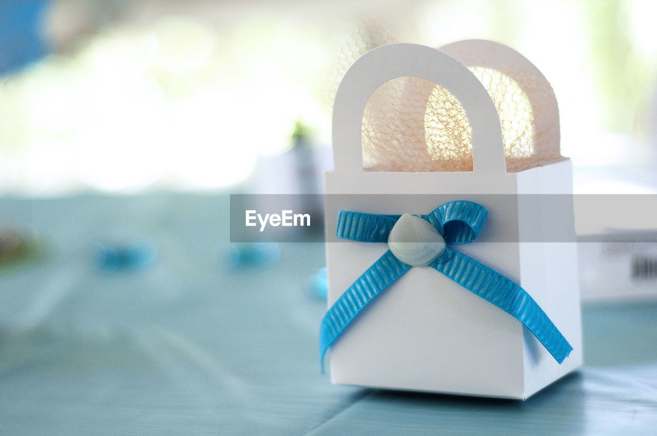 Close-up of white bag with blue ribbon on table