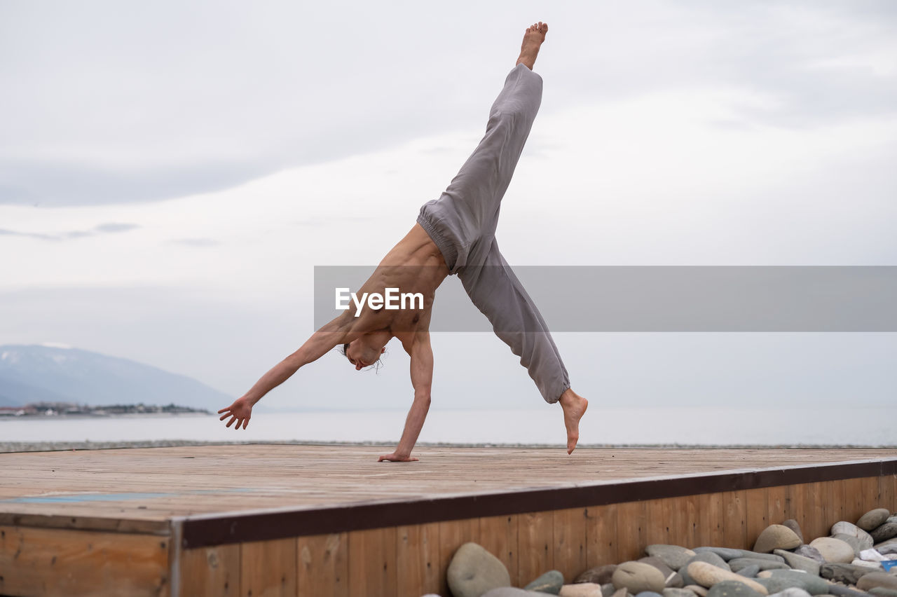 full length of woman jumping on beach against sky