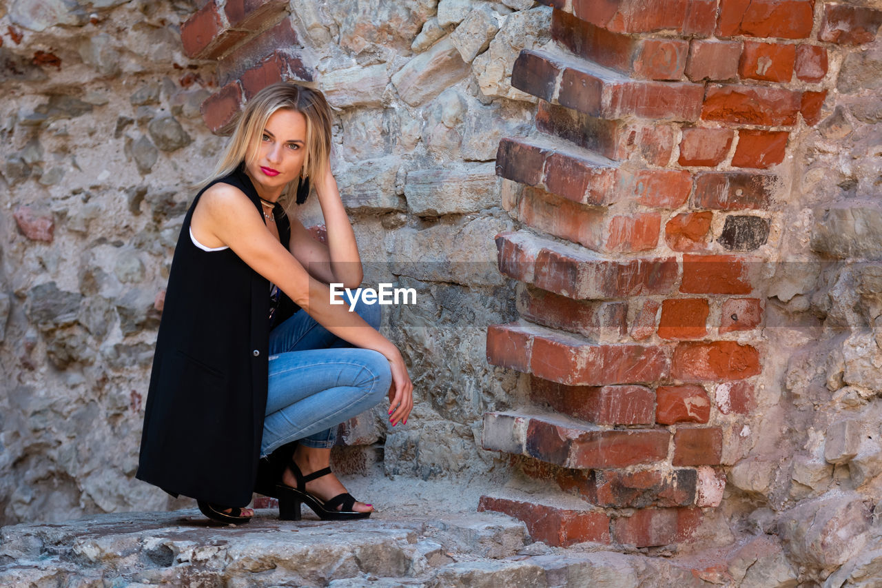 Woman sitting on brick wall