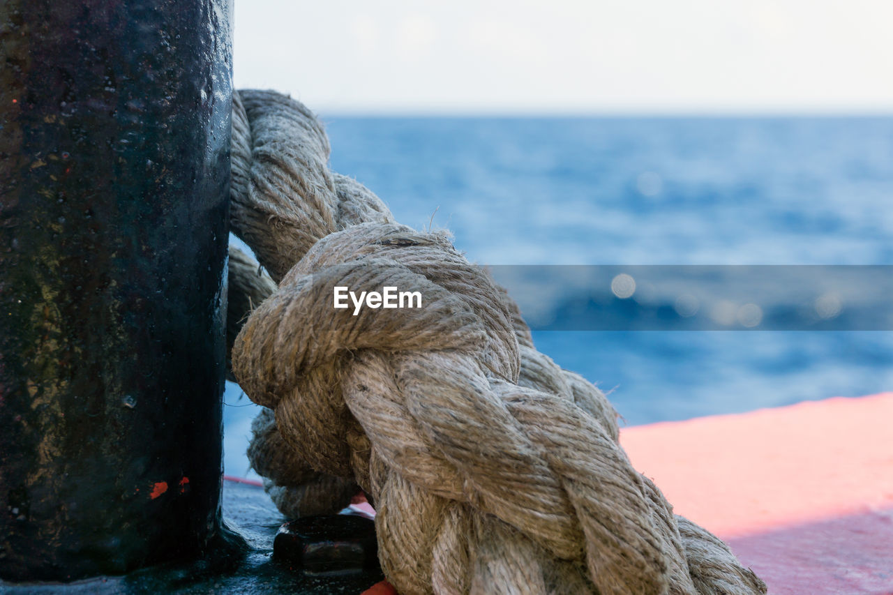 CLOSE-UP OF ROPE TIED ON WOODEN POST