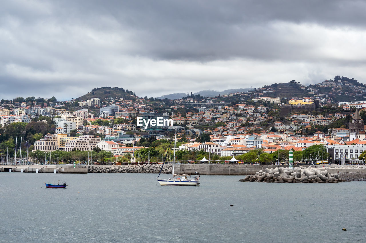 Scenic view of sea by townscape against sky