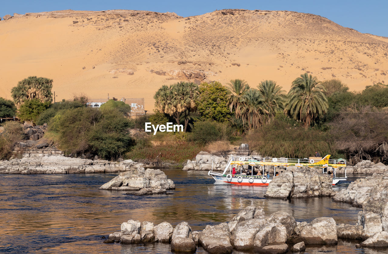 Beautiful sandy landmark of faluca traditional boat sailing in the nile river bank with vegetation