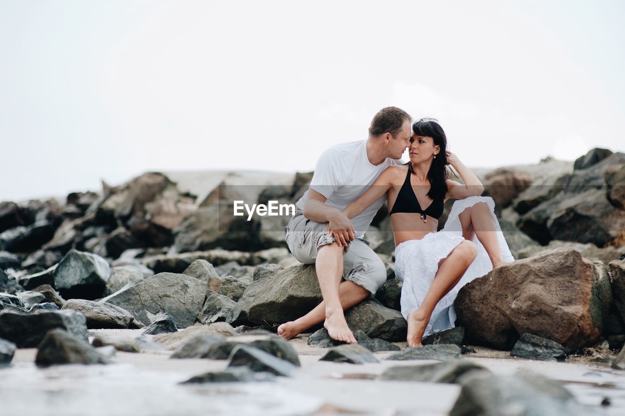 Couple kissing at beach against sky