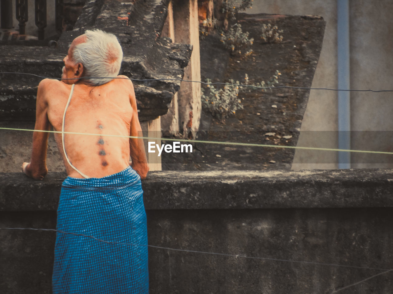 REAR VIEW OF SHIRTLESS MAN WITH WOMAN STANDING ON STAIRCASE