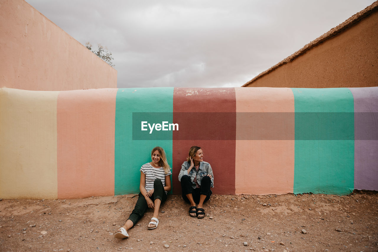 Friends sitting against wall