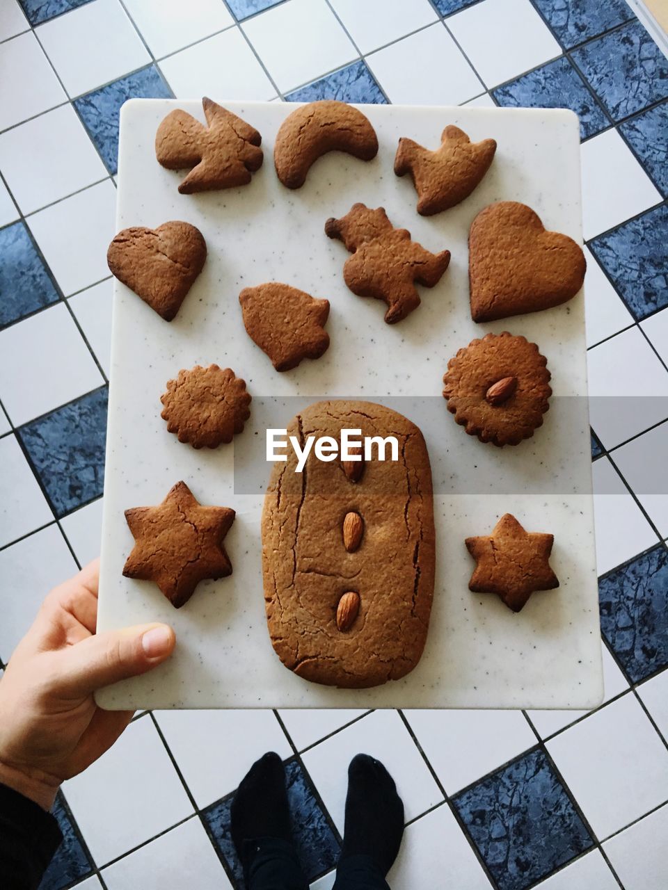 Low section of person holding cutting board with gingerbread cookies