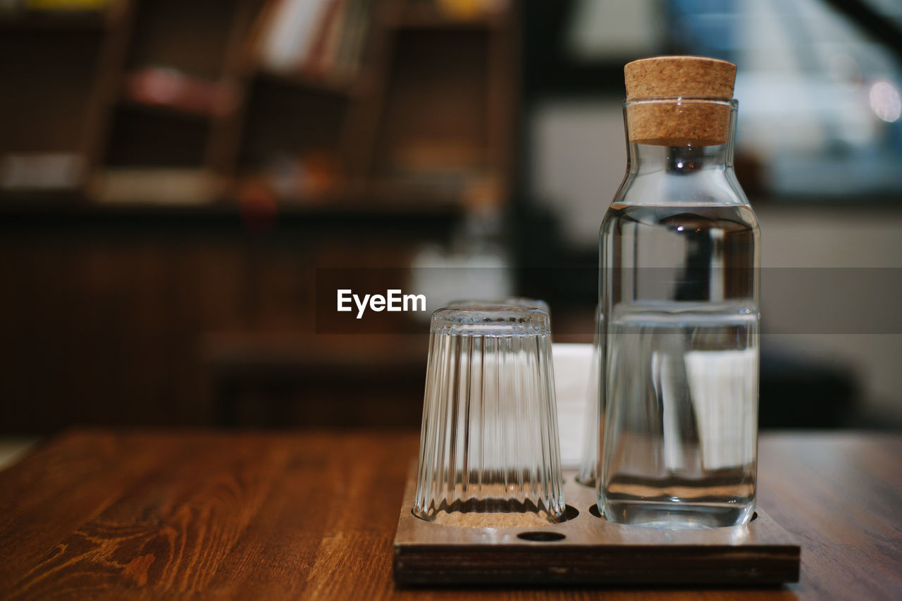 Water in glass by bottle on table in restaurant