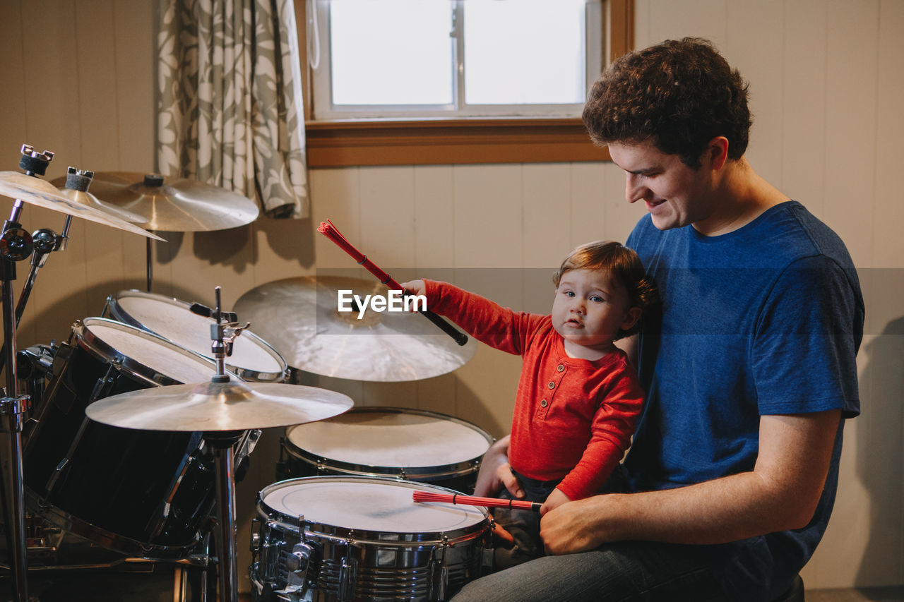 Smiling man looking at son holding drumstick