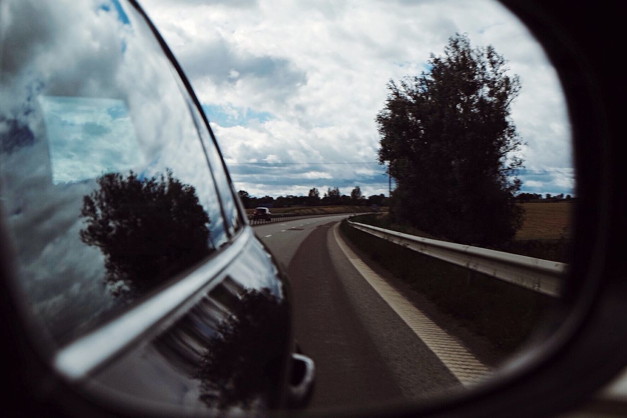 Reflection of car on road against sky on side-view mirror