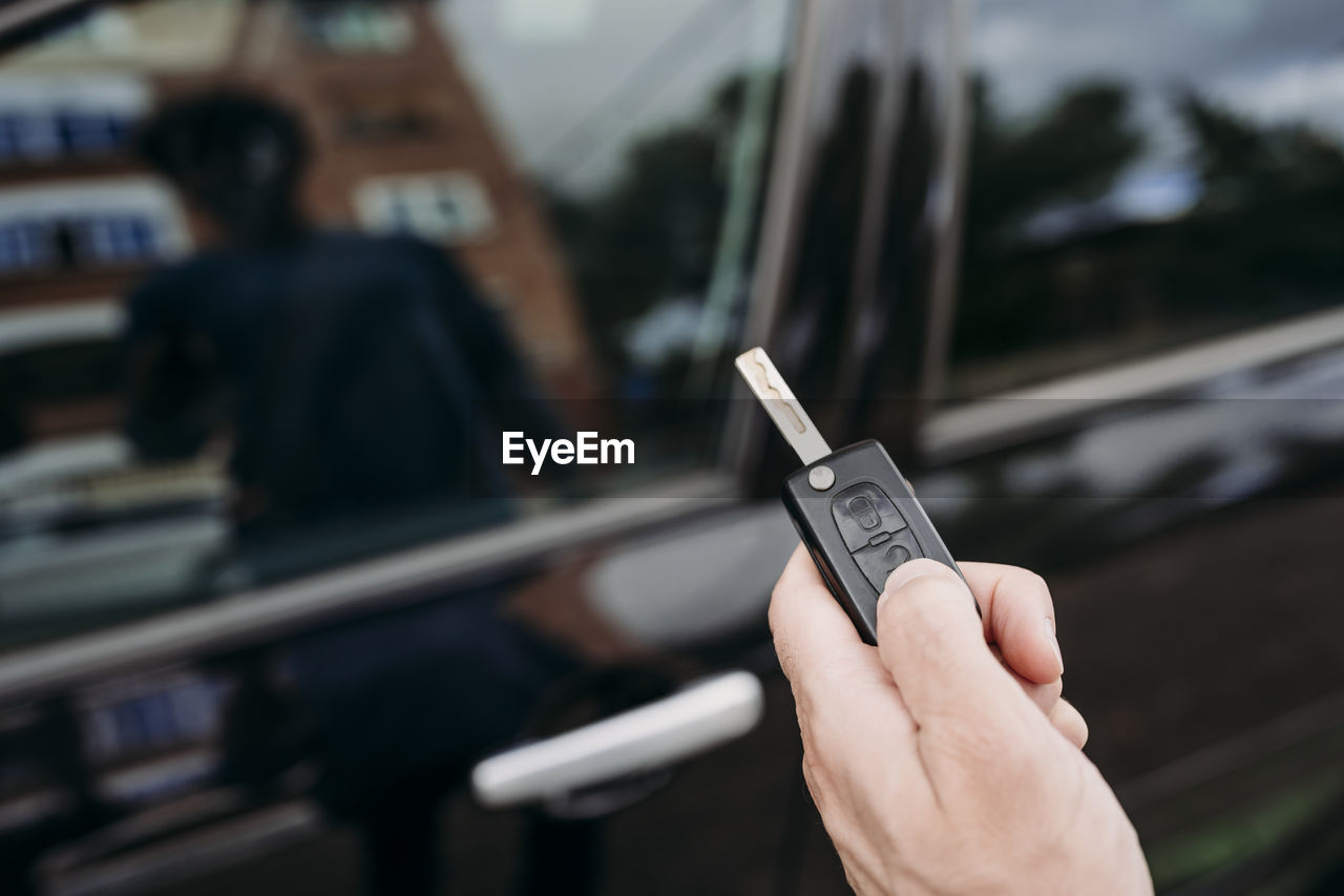 Hand of man unlocking car using key