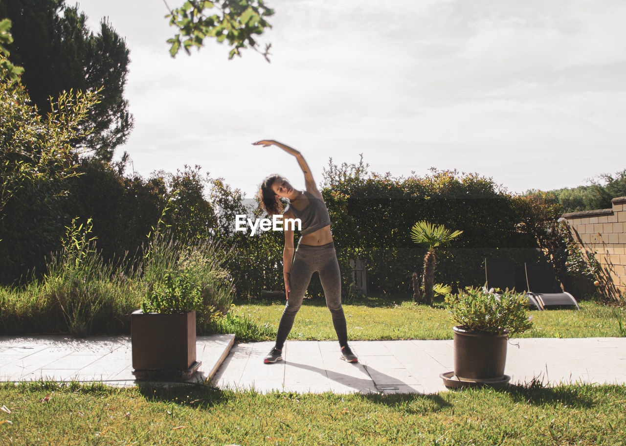 Young woman exercising in her home garden