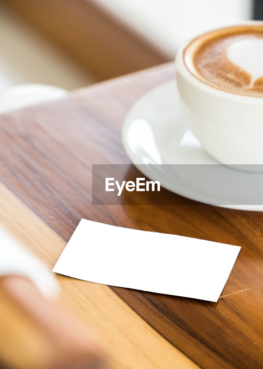 High angle view of coffee by visiting card on table