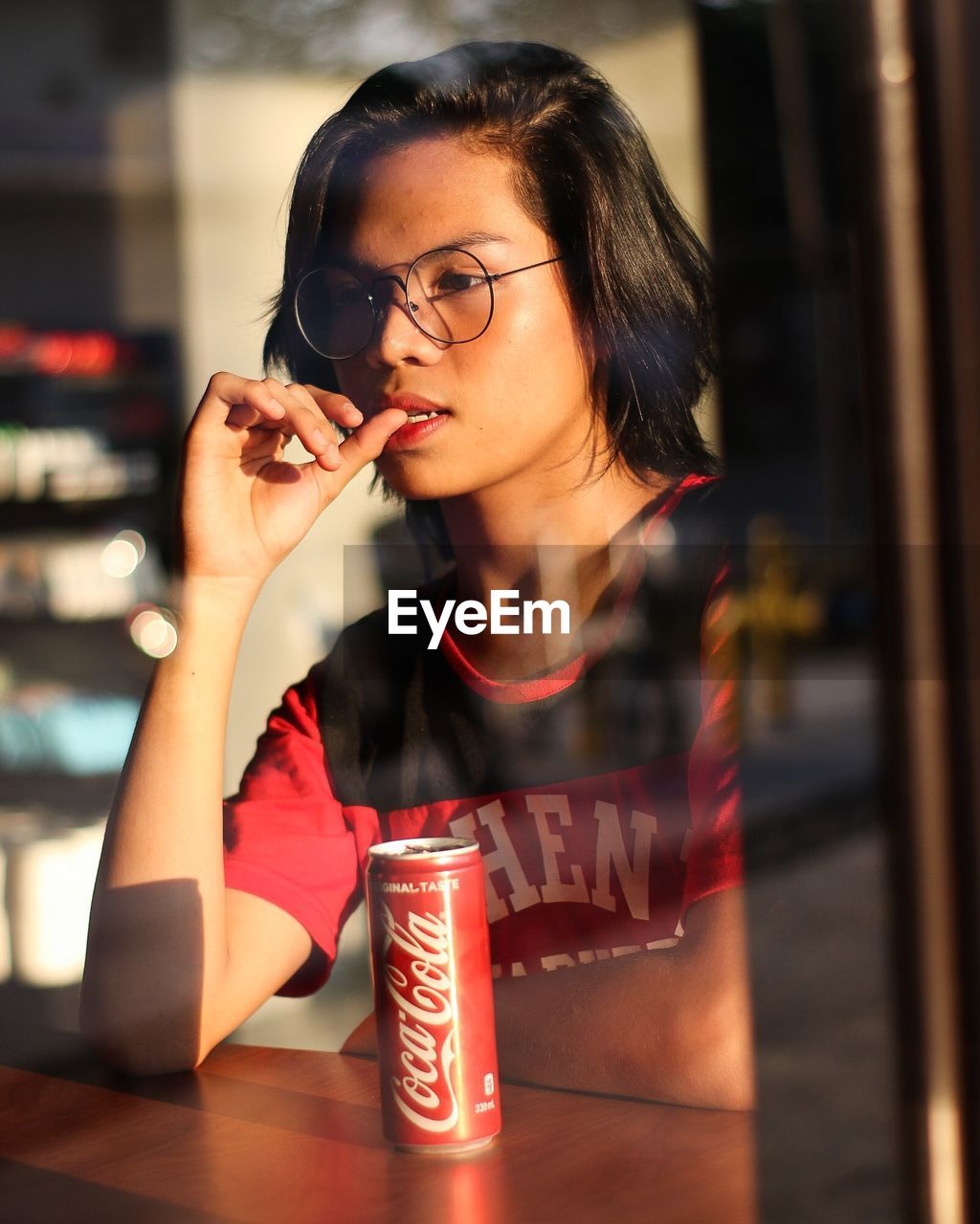 BEAUTIFUL YOUNG WOMAN DRINKING WATER FROM WHILE SITTING ON GLASS