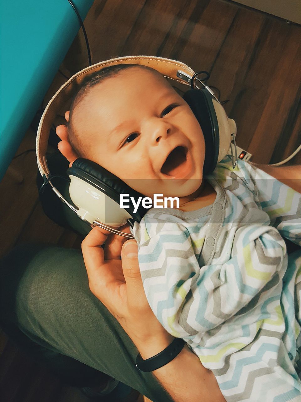 High angle view of father holding happy baby wearing headphones