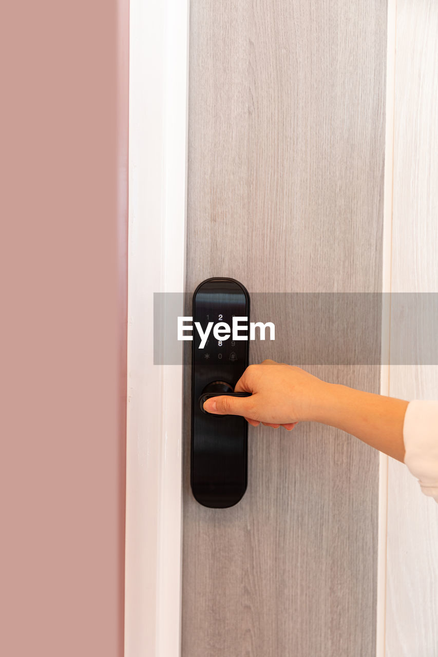 door, entrance, hand, arm, technology, one person, adult, indoors, door handle, communication, home interior, furniture, doorknob, lifestyles, holding, pushing, push button, women, knob, copy space, accessibility, security, protection, wireless technology, handle, wall - building feature, domestic life, floor, control, lock