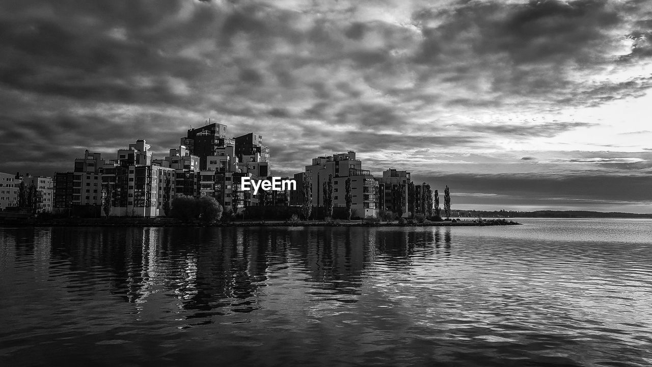 Sea and buildings in city against sky