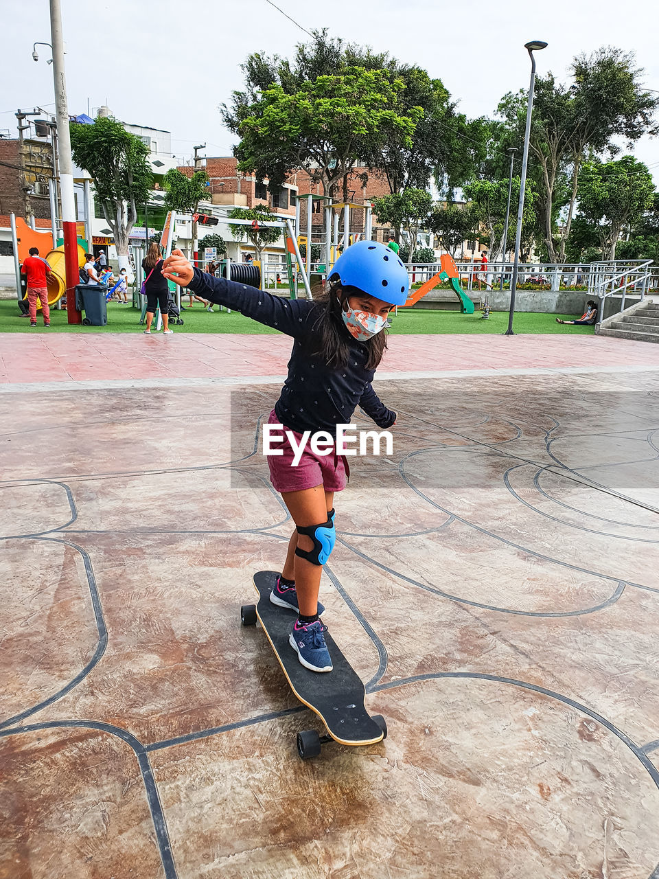 Beautiful skater girl with her protection helmet riding her longboard in the city