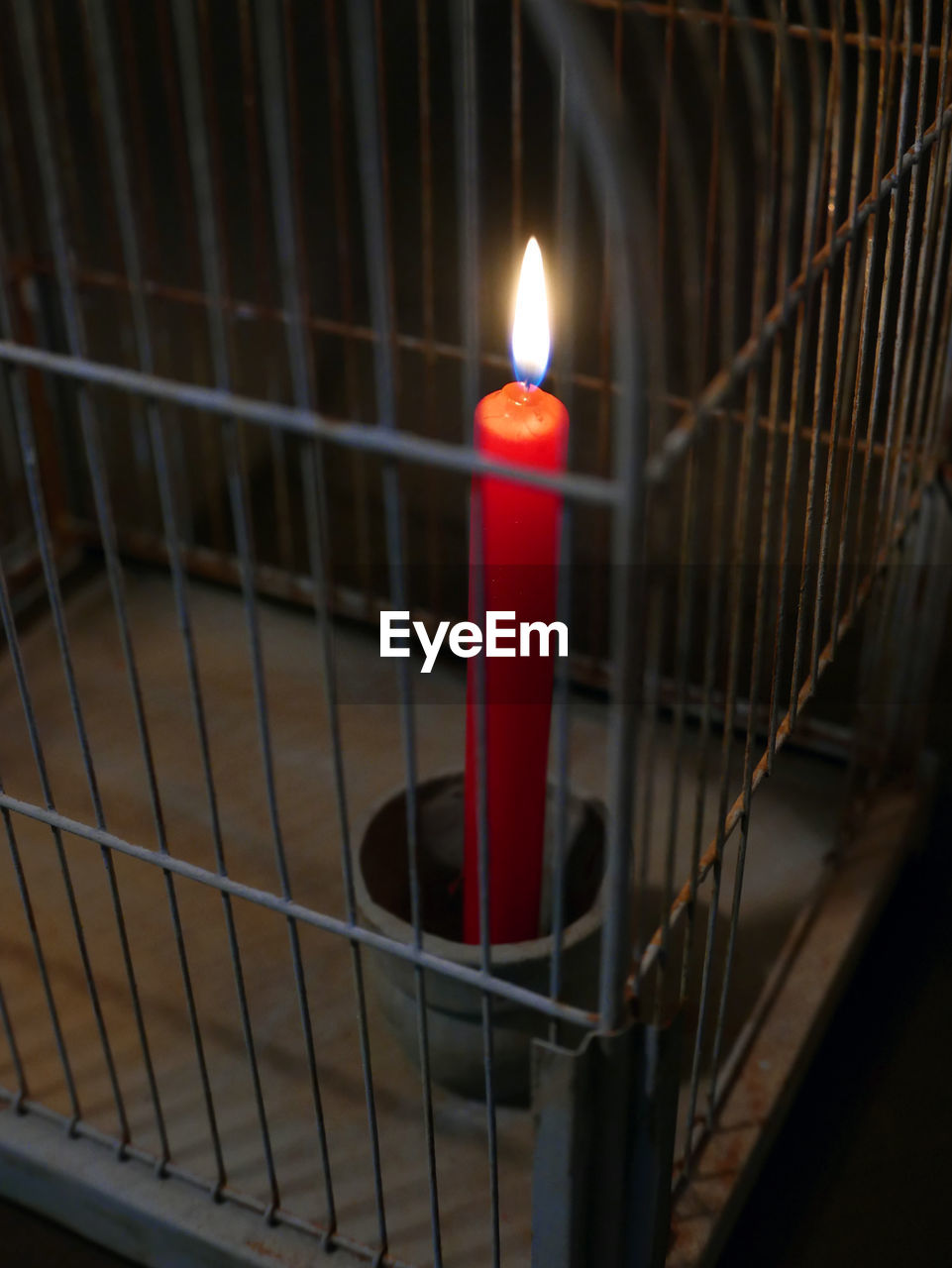 High angle view of lit candle in cage