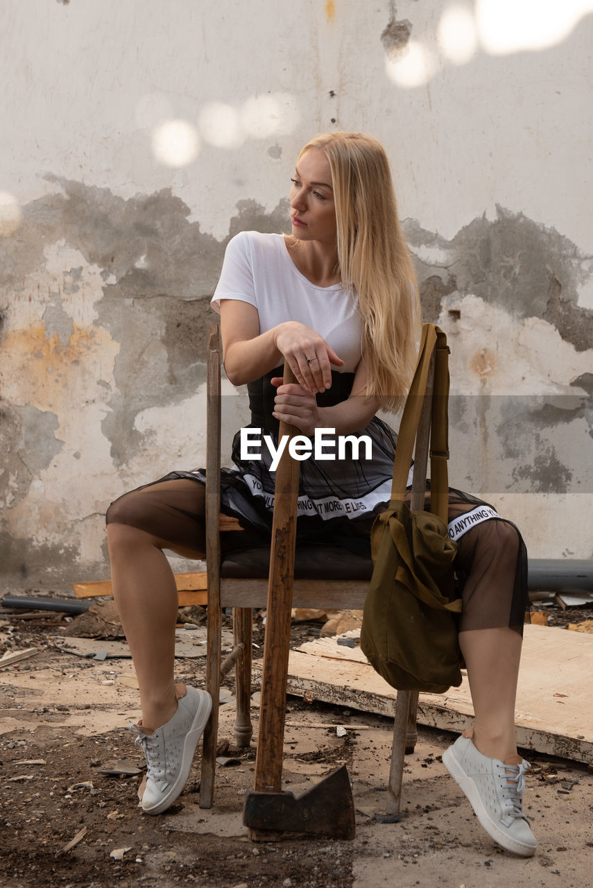 Woman sitting on a broken chair in an abandoned demolished room.