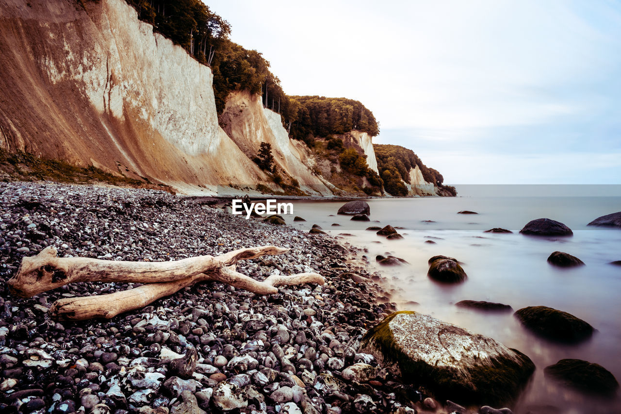 Rocks on shore at beach against sky