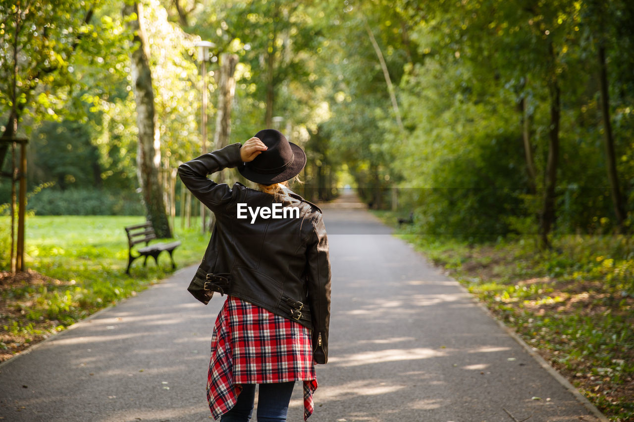 rear view of woman walking on road amidst trees