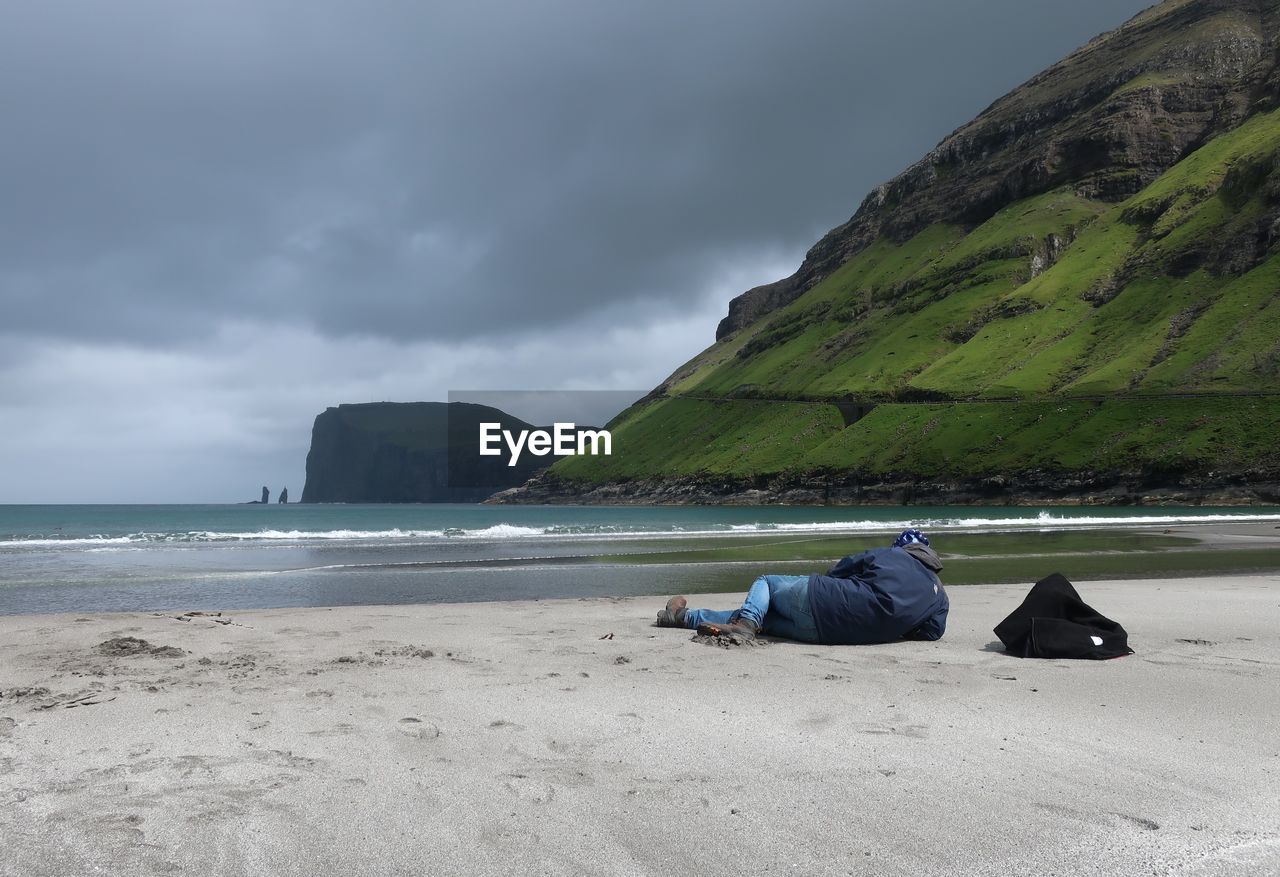 MAN LYING ON BEACH