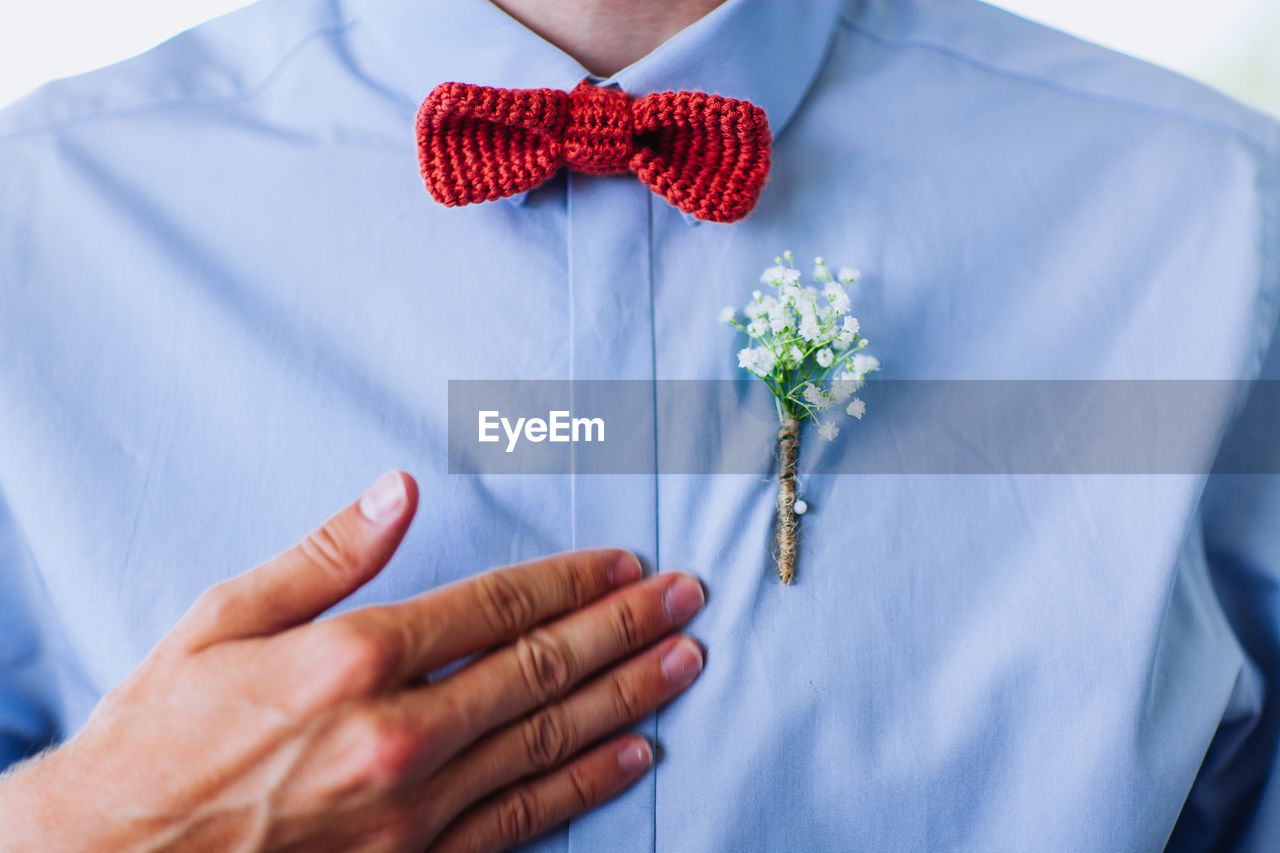 Midsection of man wearing flower on shirt