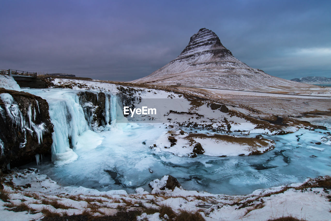 Scenic view of frozen waterfall and mountain against sky
