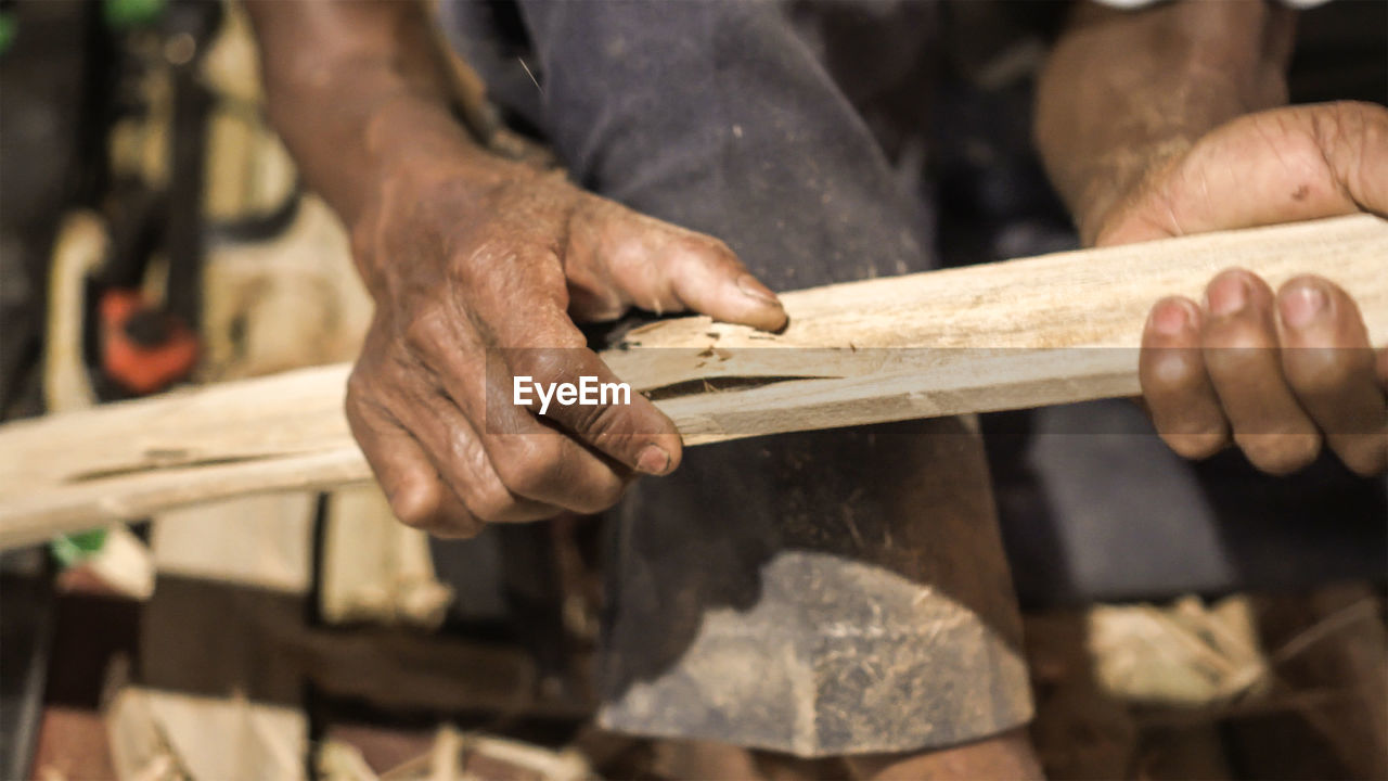 MIDSECTION OF MAN WORKING WITH WOOD